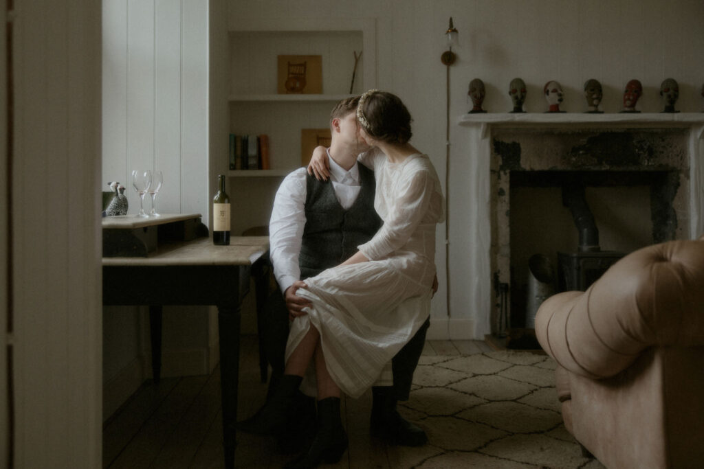 a wedding couple sitting on a chair kissing on their wedding day